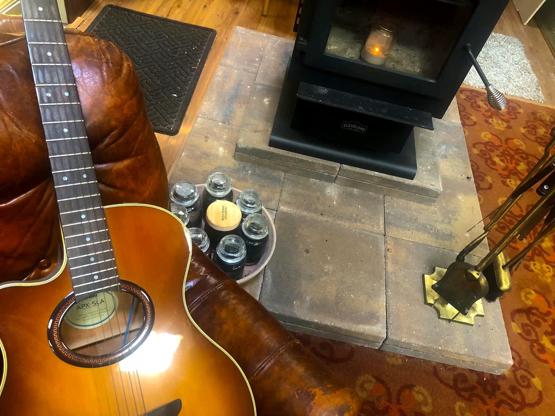 Acoustic guitar resting on a leather couch beside the wood stove at City Lights Recording Studio
